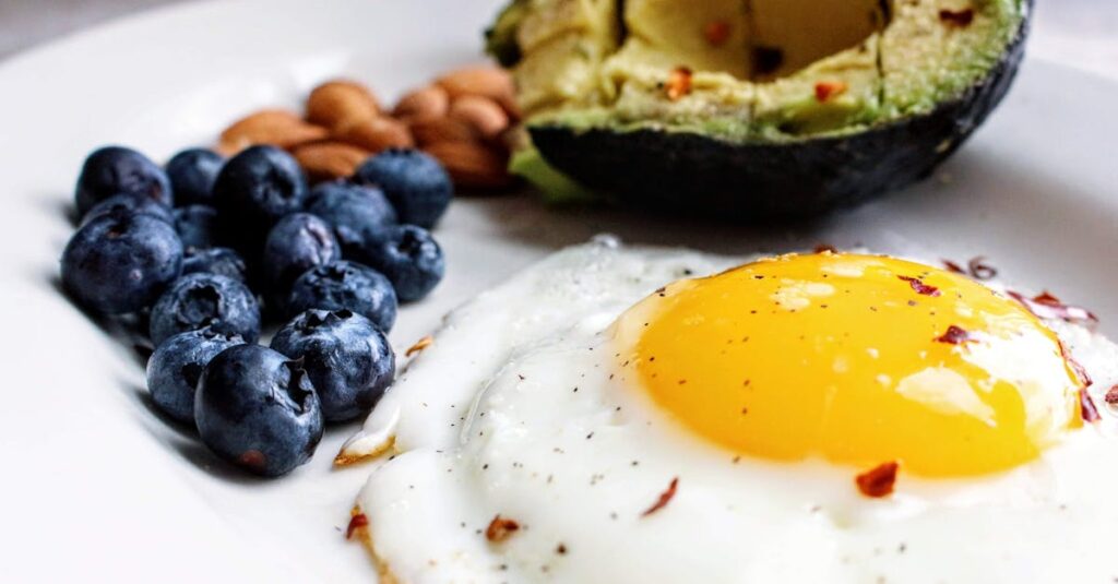 A nutritious breakfast featuring a fried egg, avocado, blueberries, and almonds.
