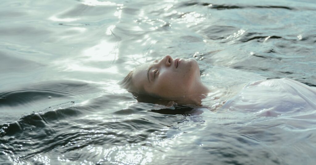 A peaceful scene of a woman in a white dress floating on a serene lake during daytime, capturing tranquility and freedom.