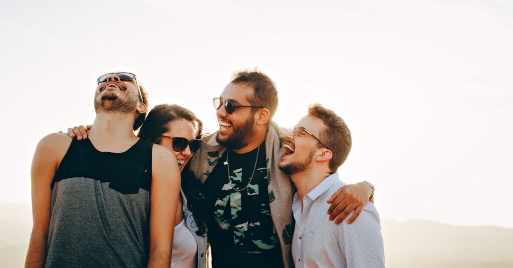 A group of young adults laughing and enjoying time together outdoors under the sun.