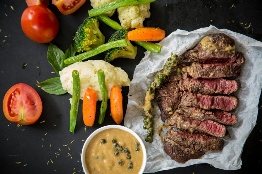 pexels-photo-769289-769289 Grilled steak served with fresh vegetables and pepper sauce, presenting a colorful and appetizing meal.